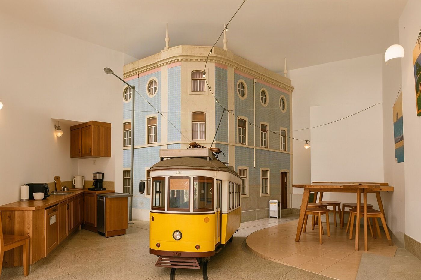 A hostel common room with a shared kitchen and long table