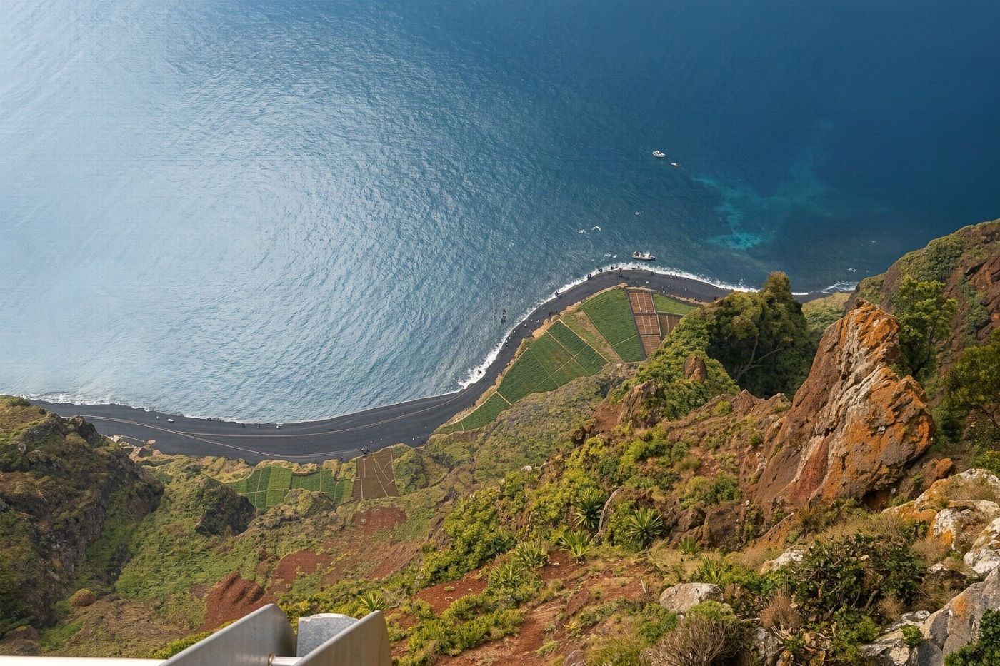 Visitors standing on the glass skywalk platform at Cabo Girão looking down at the sea.