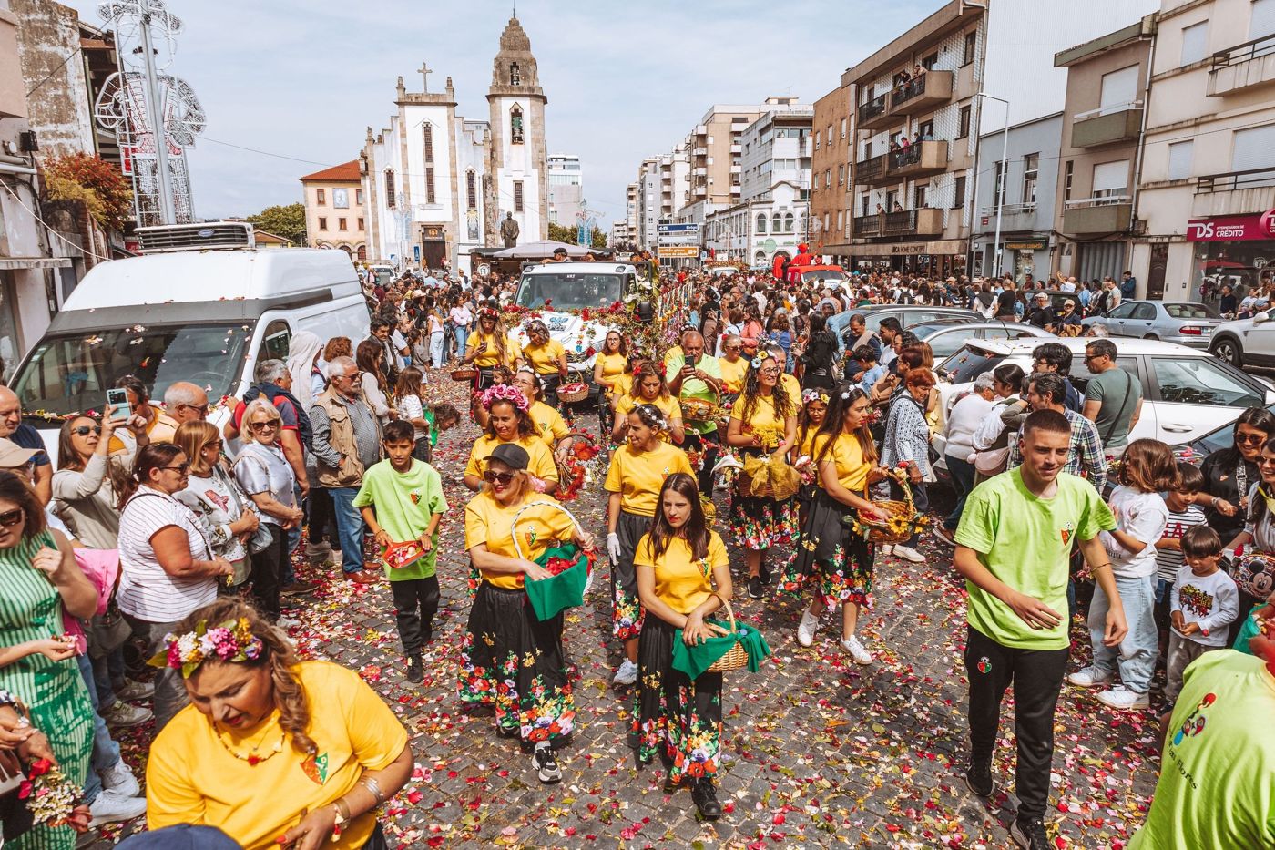 Large decorated floats and costumed troupes moving along a wide city avenue during the Funchal Carnival.
