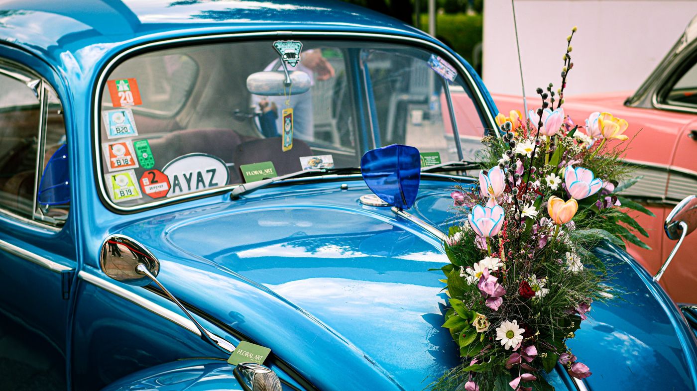 Vintage automobiles adorned with floral arrangements parked along an avenue in Funchal.