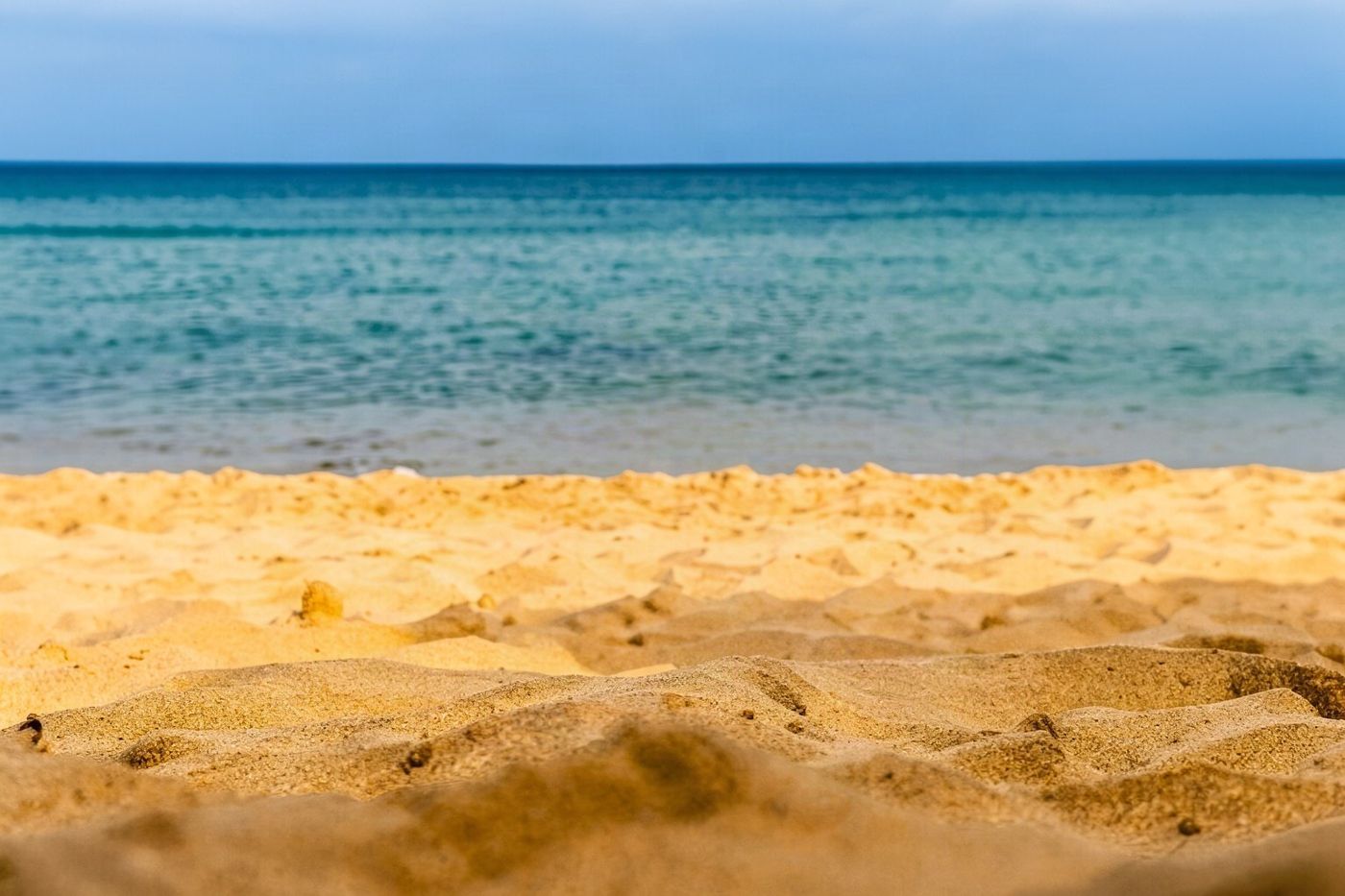 An expansive view of the golden sandy beach at Fontinha on Porto Santo island under a clear sky.