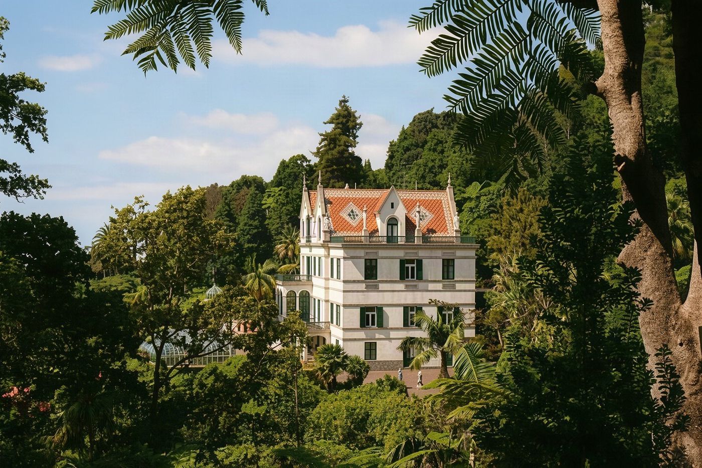 Üppige tropische Vegetation und Skulpturen innerhalb der Monte Palace Gärten mit Blick auf die darunterliegende Stadt.