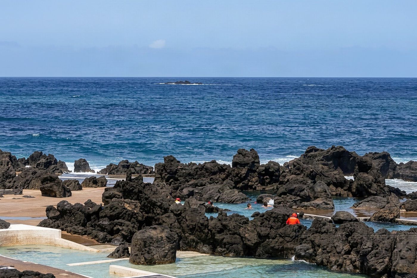 Clear blue water filling natural volcanic rock formations used for swimming at Porto Moniz on the north coast.