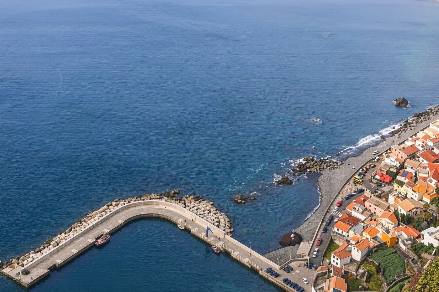 Die Betonstruktur des Pontinha-Piers, der in das klare, ruhige blaue Wasser der Bucht von Funchal ragt.