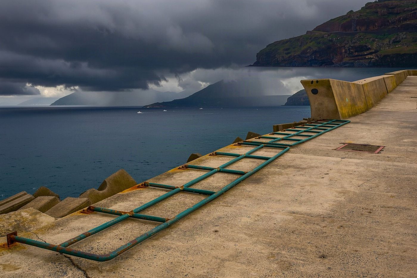 Dunkle, schwere Gewitterwolken, die über der Bucht und der Stadtlandschaft von Funchal während eines Herbstschauers aufziehen.